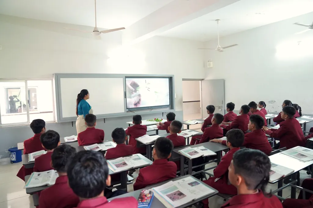 A classroom of students in maroon uniforms facing an interactive screen