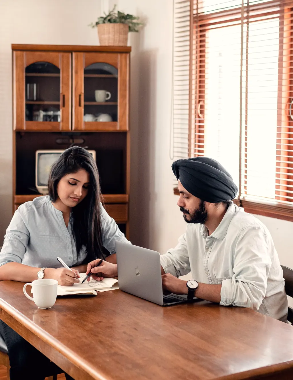 A trainer and a student working at a table with a laptop and notebook