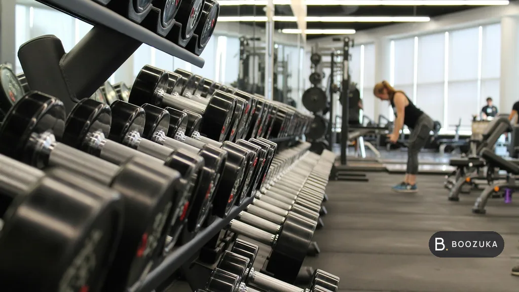 Rows of dumbbells on a rack inside a bright gym