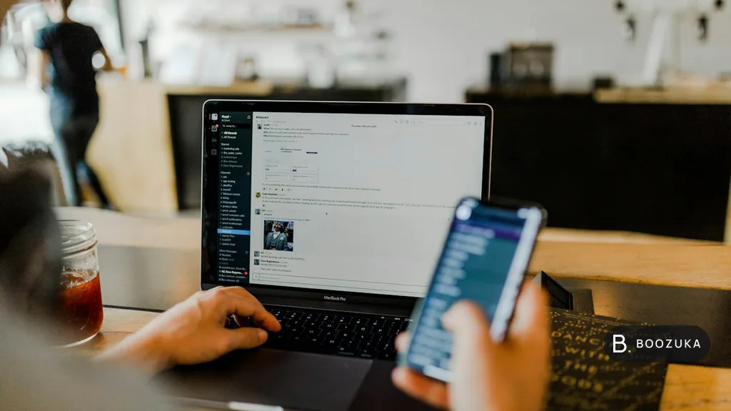 A person using a laptop and a smartphone at the same time at a desk